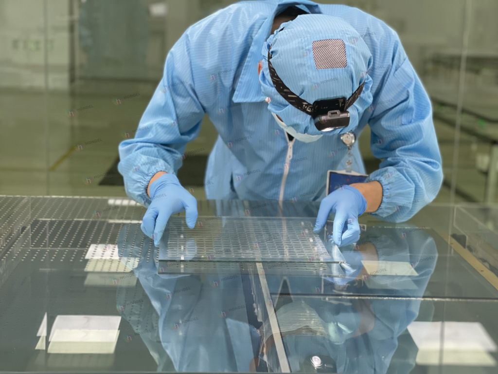 Cleanroom worker precisely aligning ITO conductive layers on architectural media glass